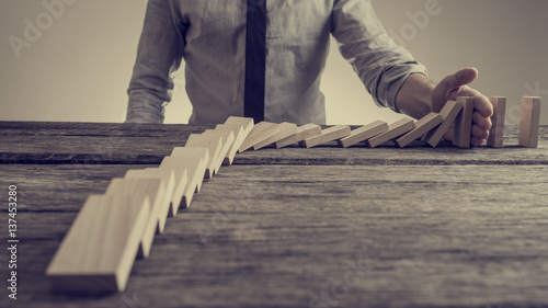 Fotomural Businessman preventing dominoes from crumbling with palm