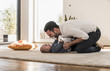 © Westend61 - Father changing diapers and playing with his baby son