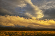 Sunset Lights Up The Clouds While Late Day Sun Casts A Warm Glow On The Grass; Iceland