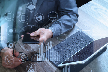 Poster - businessman hand using smart phone,mobile payments online shopping,omni channel,digital tablet docking keyboard computer,compact server on wooden desk,virtual interface icons screen