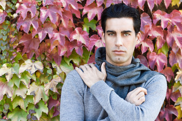 Wall Mural - Handsome man wearing winter clothes in autumn leaves background