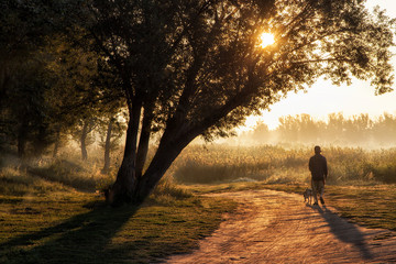 the man walking the dog early in the morning by the river