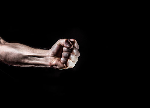 Fototapete - strong male man raised fist on a black background, power, war, protest, fist ready to fight