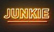 Junkie neon sign on brick wall background.