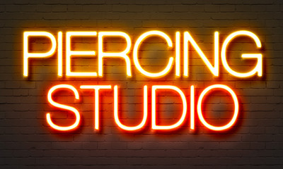 Wall Mural - Piercing studio neon sign on brick wall background.
