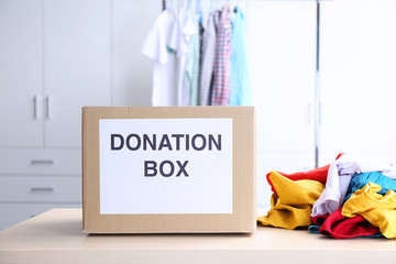 Wall Mural - Donation box with clothes on table in the room