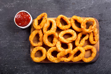 Wall Mural - onion rings with ketchup on dark background