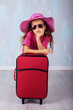 The little girl with a suitcase. The concept of travel and leisure.