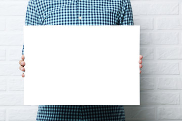 man holding blank poster on brick wall background