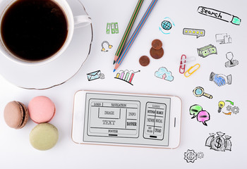 Wall Mural - website and mobile app development concept. mobile phone and coffee cup on a white office desk.