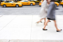 People Walking In Motion Blur Passing By Yellow Taxi Cabs In Manhattan, New York