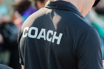 back of a coach's black color shirt with the word coach written on
