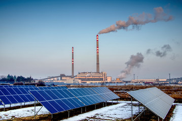 solar panels and coal power plant with smoking chimneys, ecological and outdated way of getting electricity 