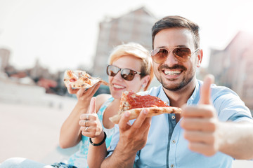 Couple eating pizza outdoors