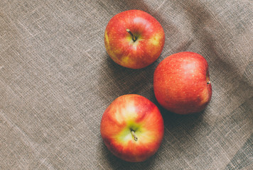 group of three red apples on rustic fabric background