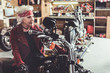© Yakobchuk Olena - Smiling pensioner sitting on motorcycle in garage