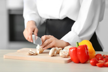 Poster - Female chef cutting mushrooms on wooden board closeup