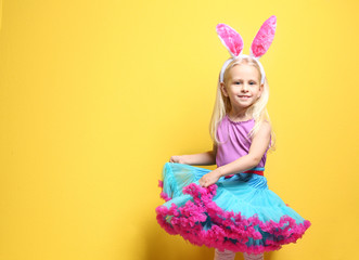 Wall Mural - Cute little girl with bunny ears on color background