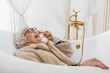 © Yakobchuk Olena - Funny senior lady with fur coat in bathtub