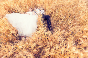 Happy bride and groom lying in a wheat field