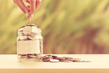 Hand Putting Coins In Glass Jar With Blank Label For Giving And Donation Concept