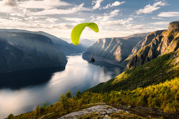 Paraglider silhouette flying over Aurlandfjord, Norway