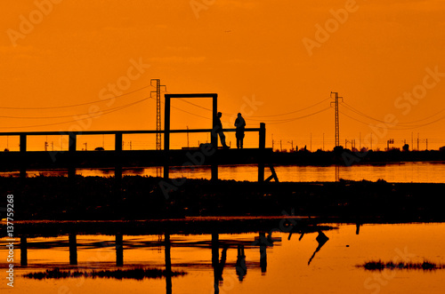 Fotografía Pareja de novios en un embarcadero al atardecer.