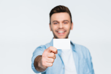 portrait of smiling man showing credit card on white, focus on foreground