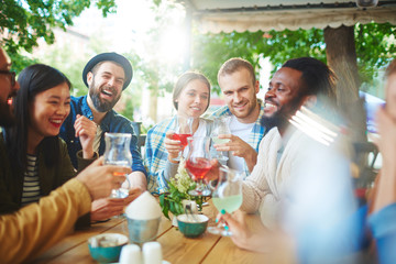 Wall Mural - Hipster buddies with drinks having talk in outdoor cafe