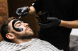 © pressmaster - Barber applying purifying mask on his client face