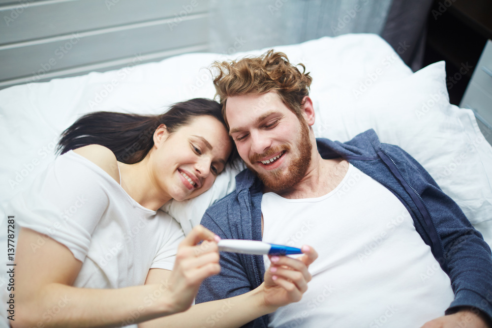 Married couple looking at positive pregnancy-test - obrazy, fototapety, plakaty 
