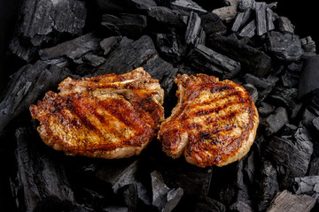 grilled meat with bone and stripes from the grill on charcoal background