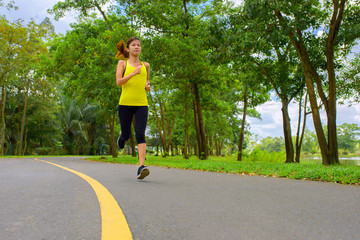 Wall Mural - Young fitness sport woman running on the road in the morning, Sun light flare , Selective focus