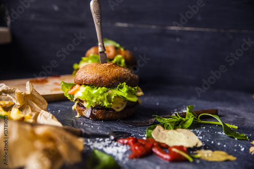 Fast food on the table: hot dog sausage and vegetables, burger with pork or beef and French fries with tomato sauce, basil leaves © lebedevaelena