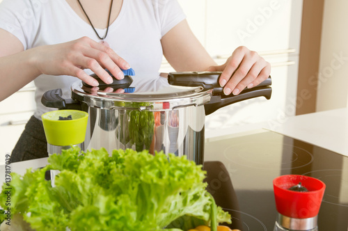 Plakat Kobieta używa szybkowaru do gotowania posiłku. Koncepcja zdrowego odżywiania.