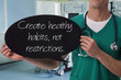 © dream@do - Male doctor holding health inspiration motivation quote on blackboard.
