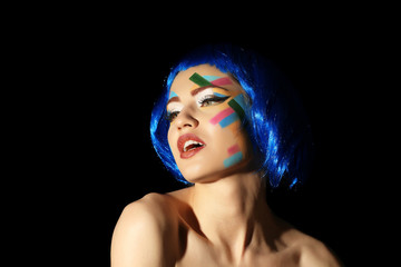 Wall Mural - Portrait of young woman with creative make up and blue hair on black background