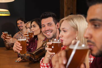 Wall Mural - Young People Group In Bar, Friends Sitting At Wooden Counter Pub, Drink Beer Communication Party Celebration