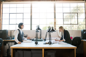 Wall Mural - Male female coworkers busy at work in beautiful industrial office workspace with large windows, sunlight