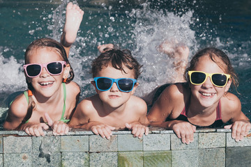 Three happy children  playing on the swimming pool at the day time.