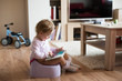 Little girl at home sitting on potty playing with tablet