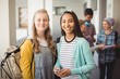 © WavebreakMediaMicro - Portrait of smiling schoolgirls standing in corridor