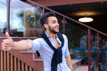 Wall Mural - Cheerful young man looks Muslim smiling and showing hand gesture