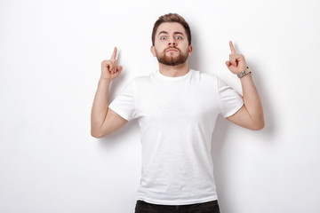 Wall Mural - handsome man with beard pointing up. young man looking at camera