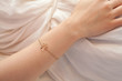 Detail of woman's hand with angel bracelet resting on her belly while relaxing