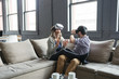 © Cavan Images - Happy business people wearing virtual reality simulator while sitting on sofa in office