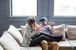 © Cavan Images - Happy coworkers wearing virtual reality simulators while sitting on sofa in office
