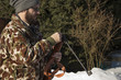 Mężczyzna w zimowym lesie przeładowuje broń pneumatyczną. Mężczyzna w białym zimowym lesie ładuje broń długą Mężczyzna ładuje wiatrówkę w zimowym zaśnieżonym lesie.