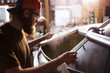 © Cavan Images - Brewer looking in machinery at brewery