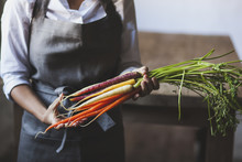 Midsection Of Woman Holding Various Carrots While Standing In Kitchen